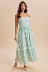 woman wearing a light green floral maxi dress with adjustable straps and frill details