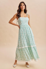 woman wearing a teal floral maxi dress with ruffled straps and a tiered skirt, styled with white flats
