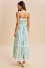 woman wearing a mint green floral maxi dress with a smocked bodice and ruffled hem, facing away from the camera