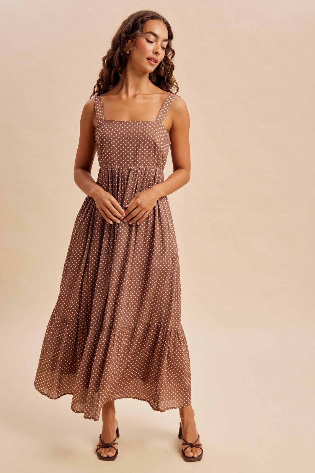 woman wearing a brown polka dot maxi dress with a square neckline and a tiered skirt