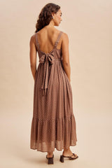 woman wearing a brown polka dot maxi dress with a tied back and flared hem