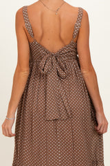 woman wearing a brown polka dot maternity dress with adjustable straps and a tied back detail