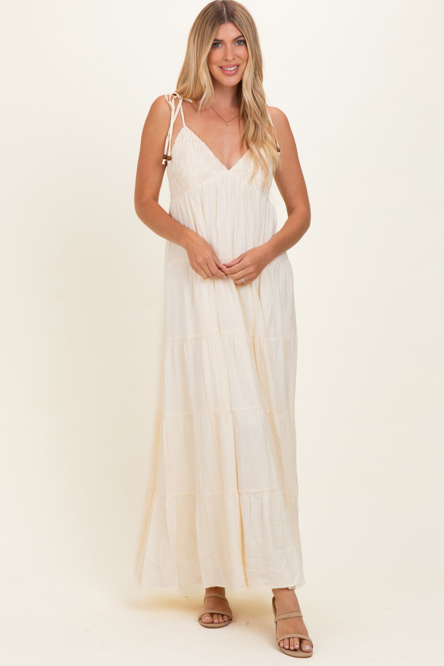 woman wearing a cream tiered maxi dress with adjustable spaghetti straps and a smocked bodice