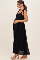 woman wearing a black lace maternity maxi dress with tie straps and a visible baby bump