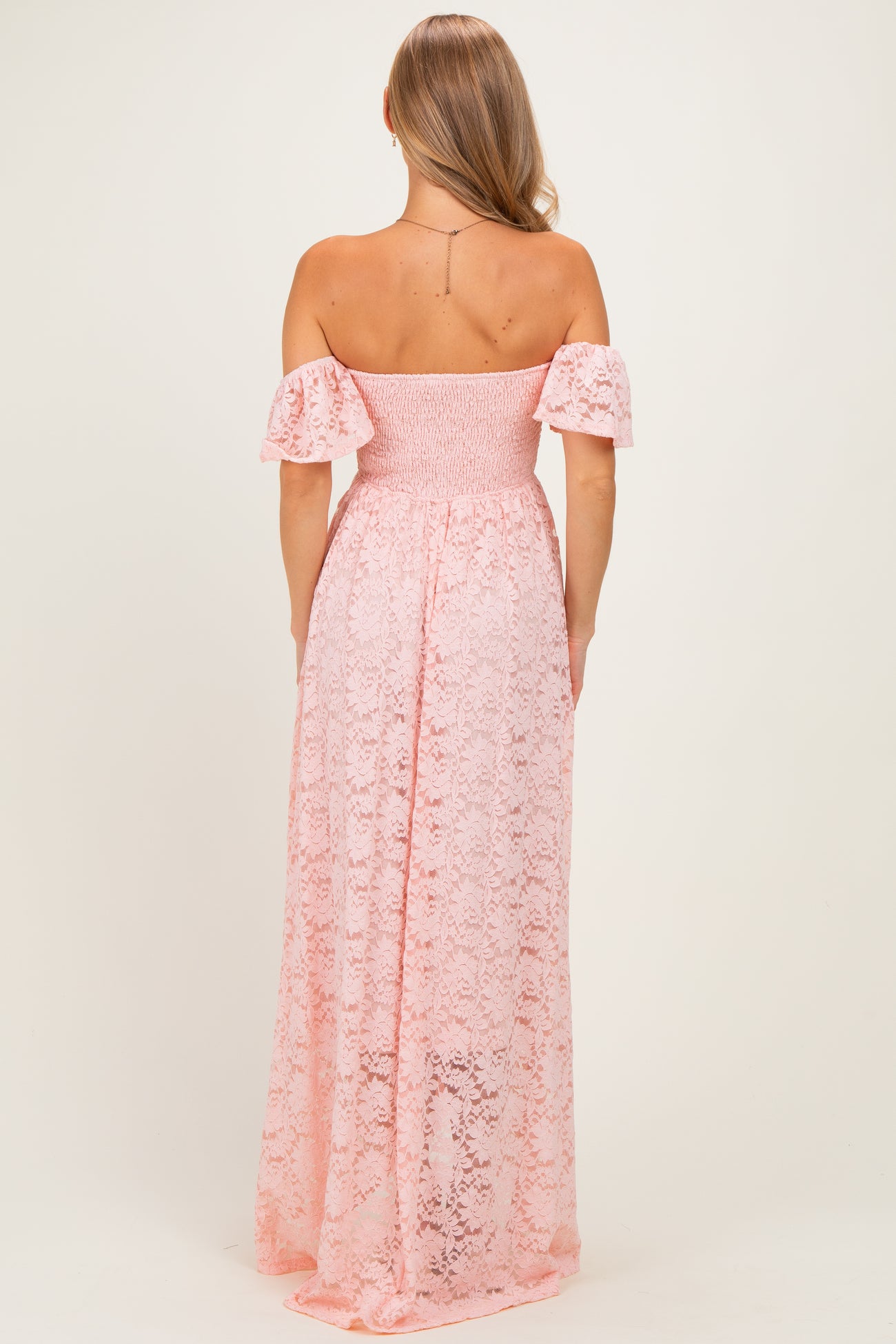 woman wearing a pink lace off-the-shoulder maxi dress, view from the back