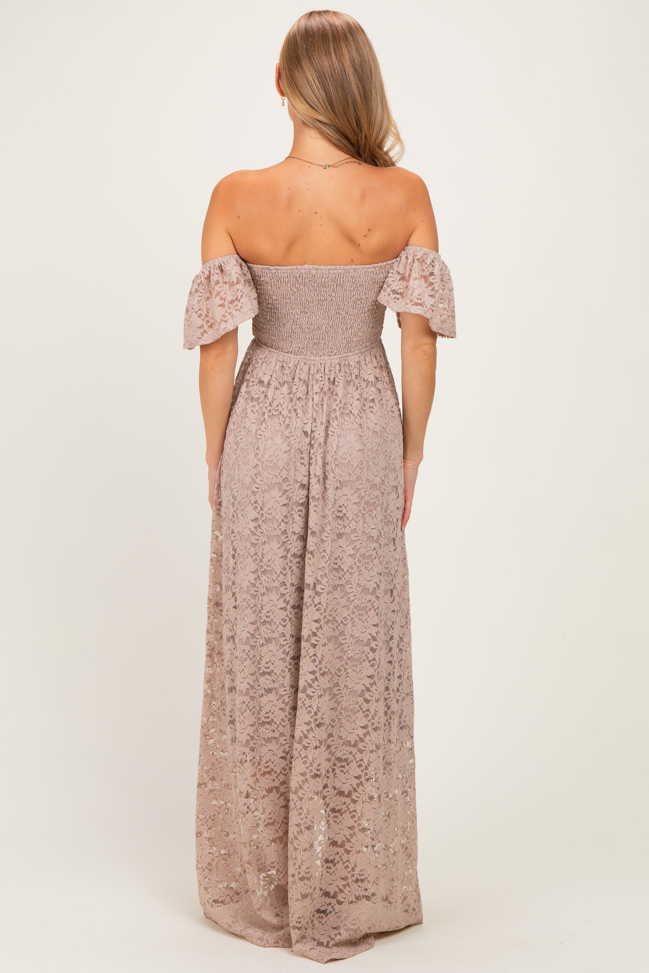 woman wearing a dusty pink off-the-shoulder lace maxi dress with puff sleeves, showing the back view