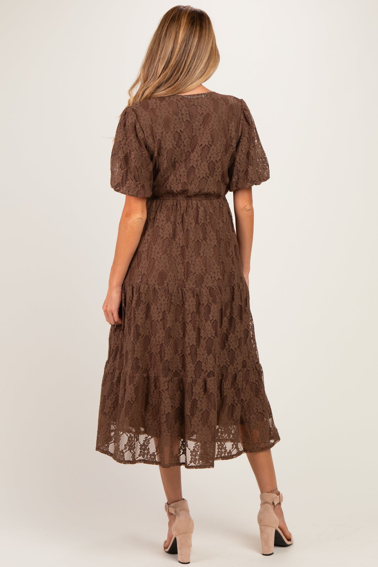 woman wearing a brown lace maternity dress with short sleeves and a flowing skirt, showing the back view