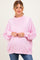 woman wearing a light pink oversized maternity sweat shirt with a ruffled neck and a visible baby bump