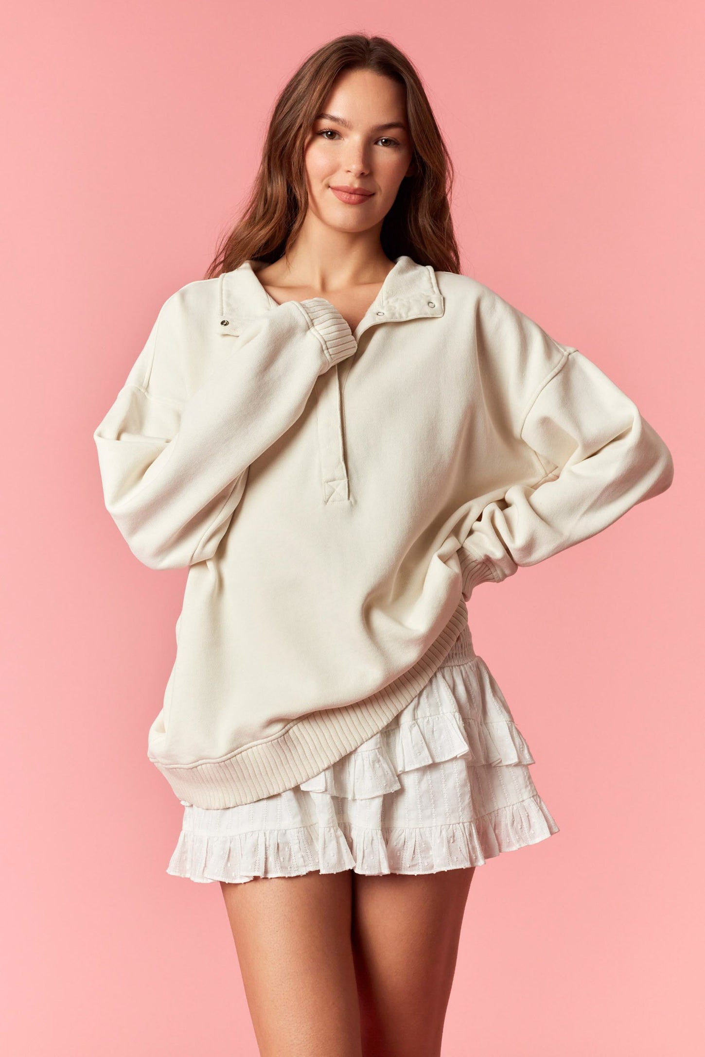 woman wearing an oversized cream pullover sweatshirt paired with a white ruffled mini skirt