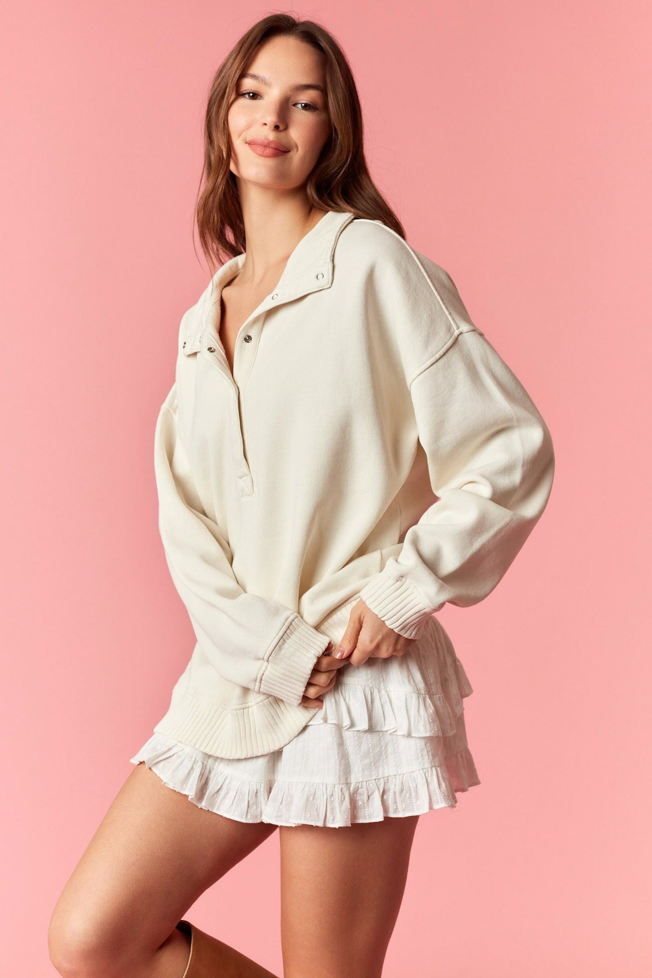 woman wearing a cream oversized pullover sweatshirt and a white ruffled mini skirt