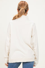 woman wearing a light beige oversized maternity sweatshirt, viewed from the back