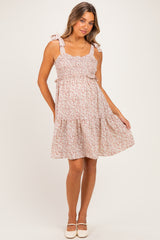 woman wearing a floral print pink maternity sundress with tie straps and a baby bump visible