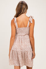 woman wearing a back view of a smocked floral maternity dress with bow straps