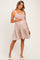woman wearing a floral print maternity dress with tie straps, cradling her baby bump