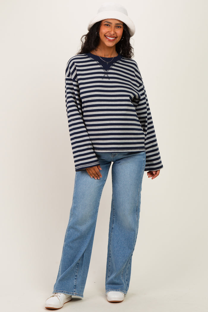 woman wearing a navy and white striped maternity sweater with relaxed fit and blue jeans, smiling while standing