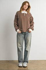 woman wearing a brown and cream striped long sleeve polo shirt and light blue baggy jeans