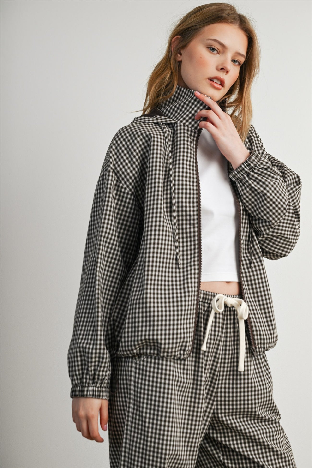 woman wearing a black and white checked zip-up jacket with a high collar and matching pants