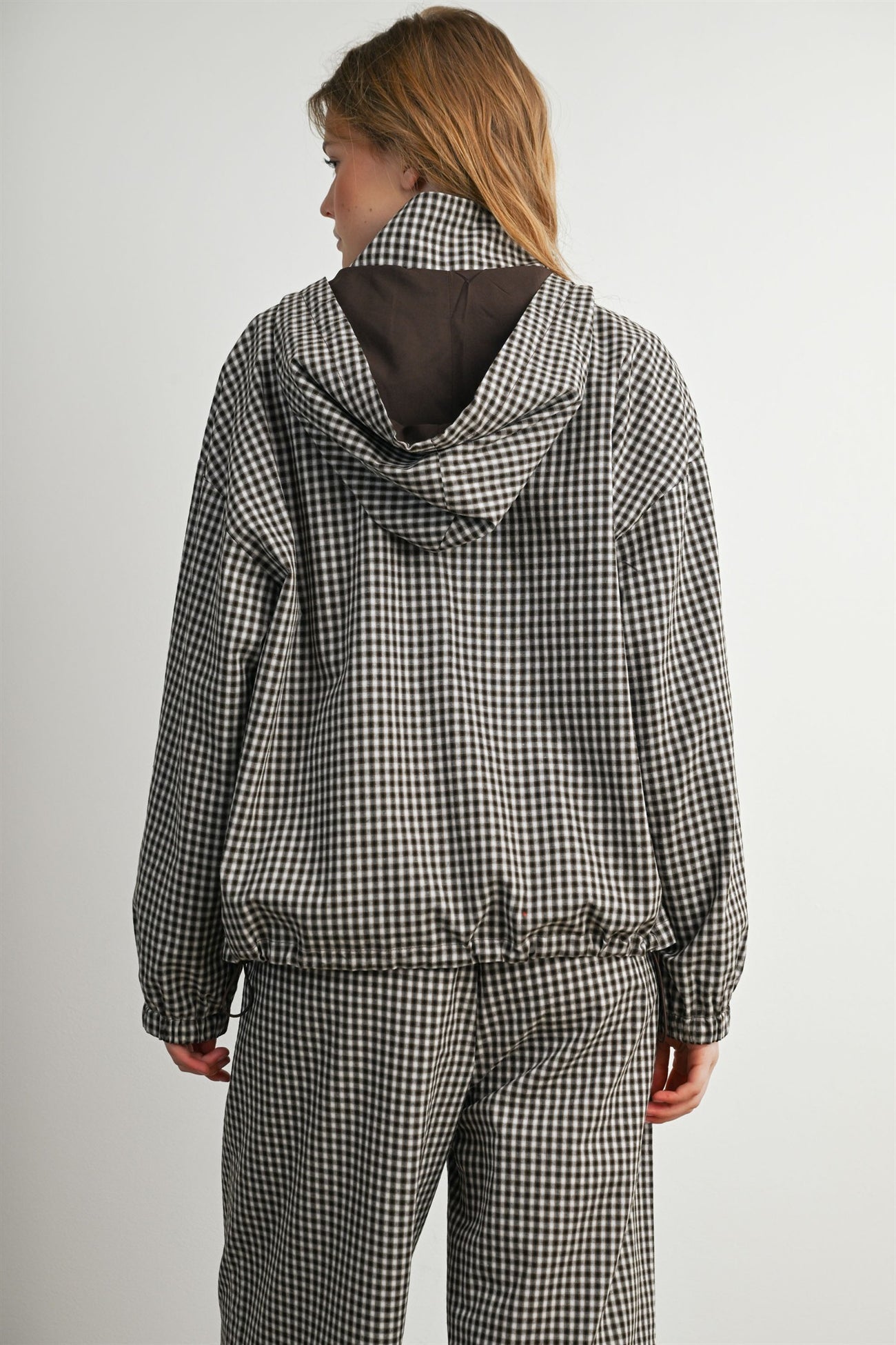woman wearing a black and white checkered jacket with a hood, facing away from the camera