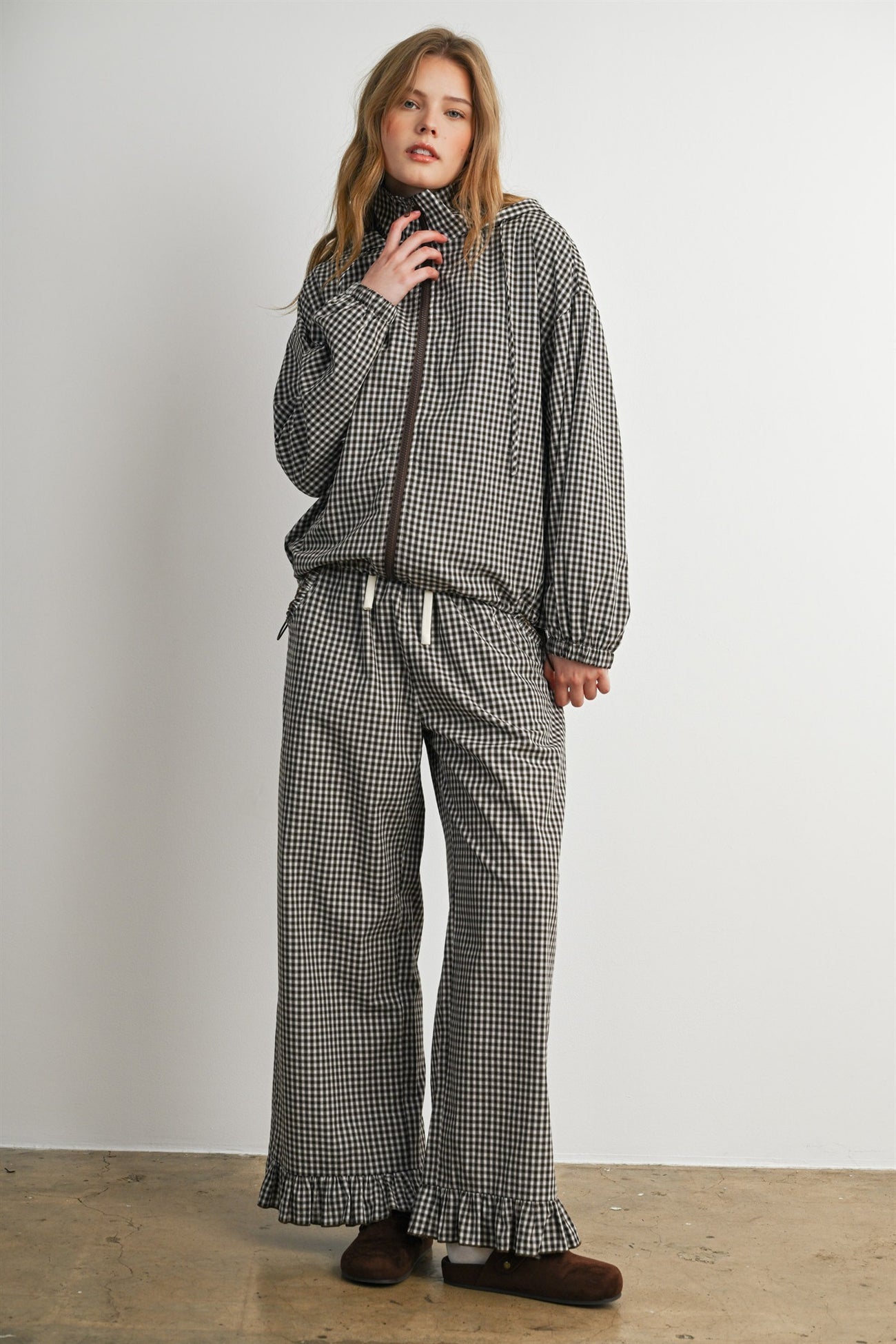 woman wearing a checkered black and white zip-up jacket and matching wide-leg pants with ruffled hems