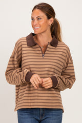 woman wearing a brown and tan striped pullover with a zip neckline and contrast collar, smiling at the camera