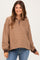 woman wearing a brown striped maternity pullover with a quarter zip and relaxed fit, smiling at the camera