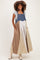woman wearing a patchwork maternity maxi dress with denim and print patterns, featuring pockets and a relaxed fit