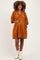 woman wearing an orange maternity dress with a plunging neckline, holding her baby bump and smiling