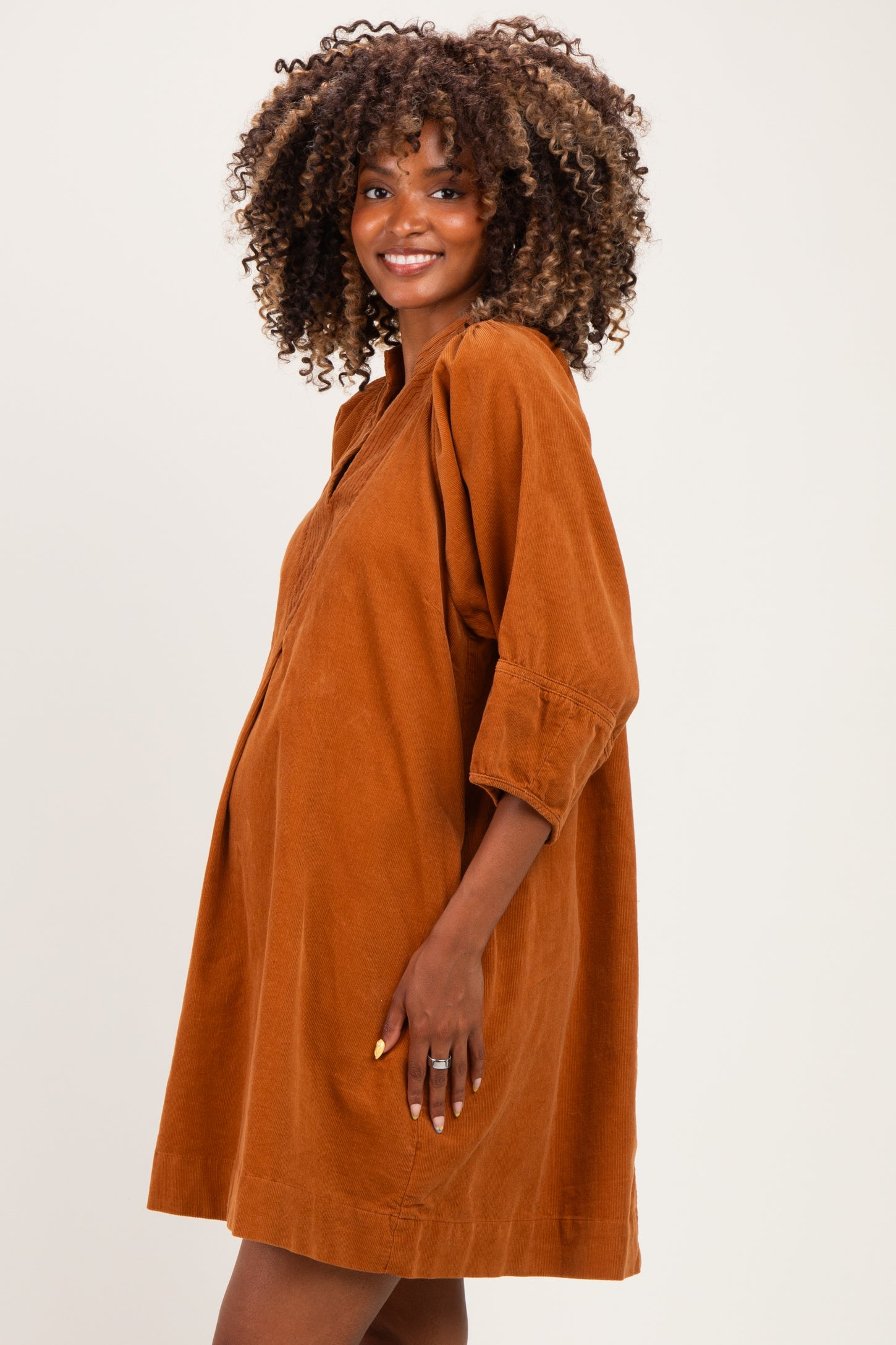 woman wearing a rust-colored maternity dress with three-quarter sleeves and a relaxed fit, showing her baby bump
