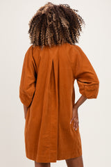 woman wearing an orange corduroy maternity dress with a back pleat and three-quarter sleeves