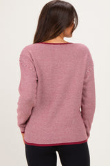 woman wearing a maroon and white striped maternity sweater, view from the back, paired with black leggings