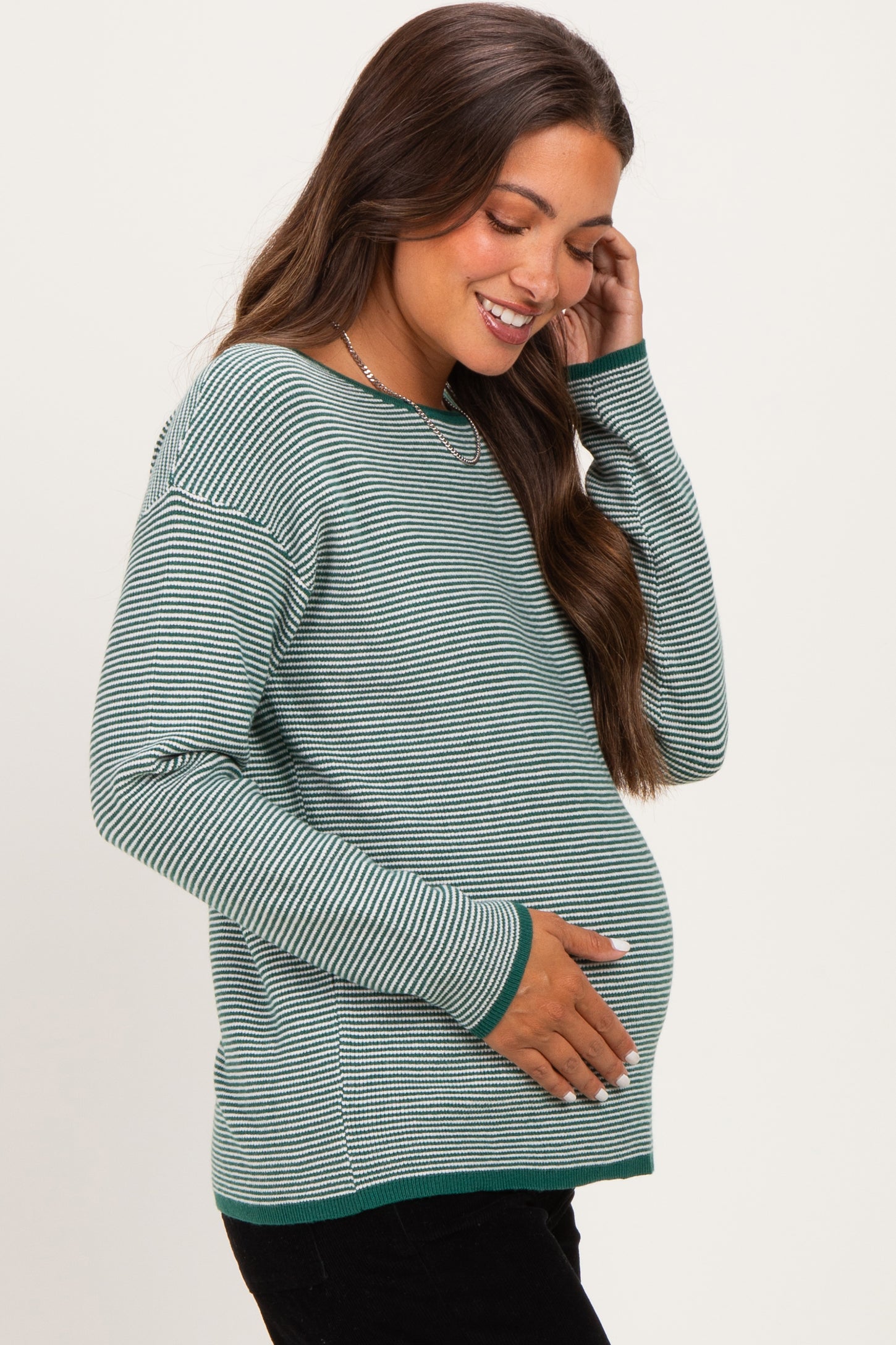 woman wearing a green and white striped maternity sweater and holding her baby bump