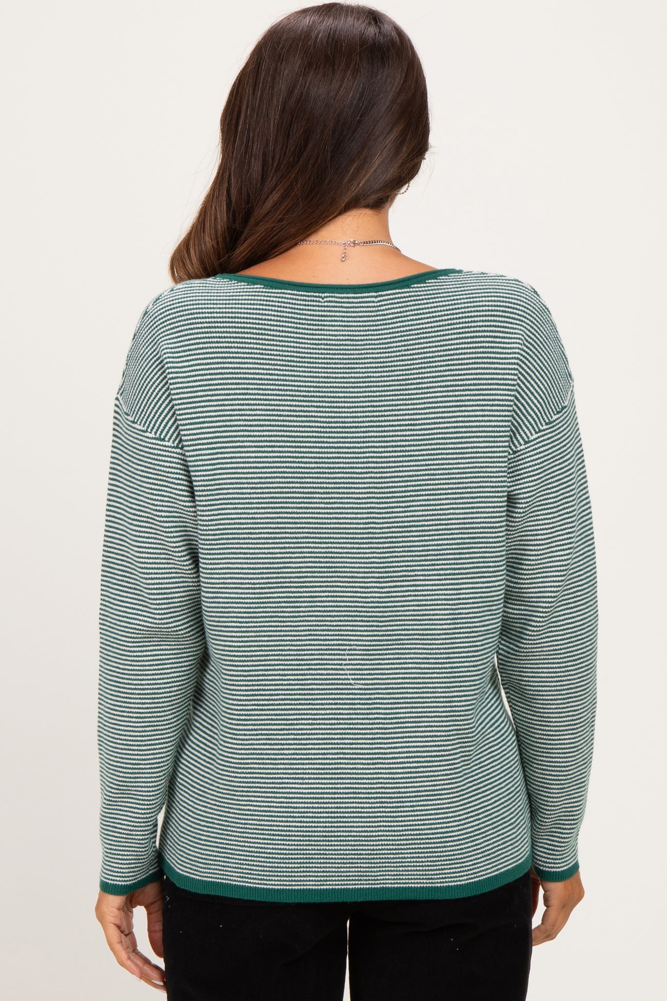 woman wearing a green and white striped maternity sweater, back view, with a relaxed fit and scoop neckline