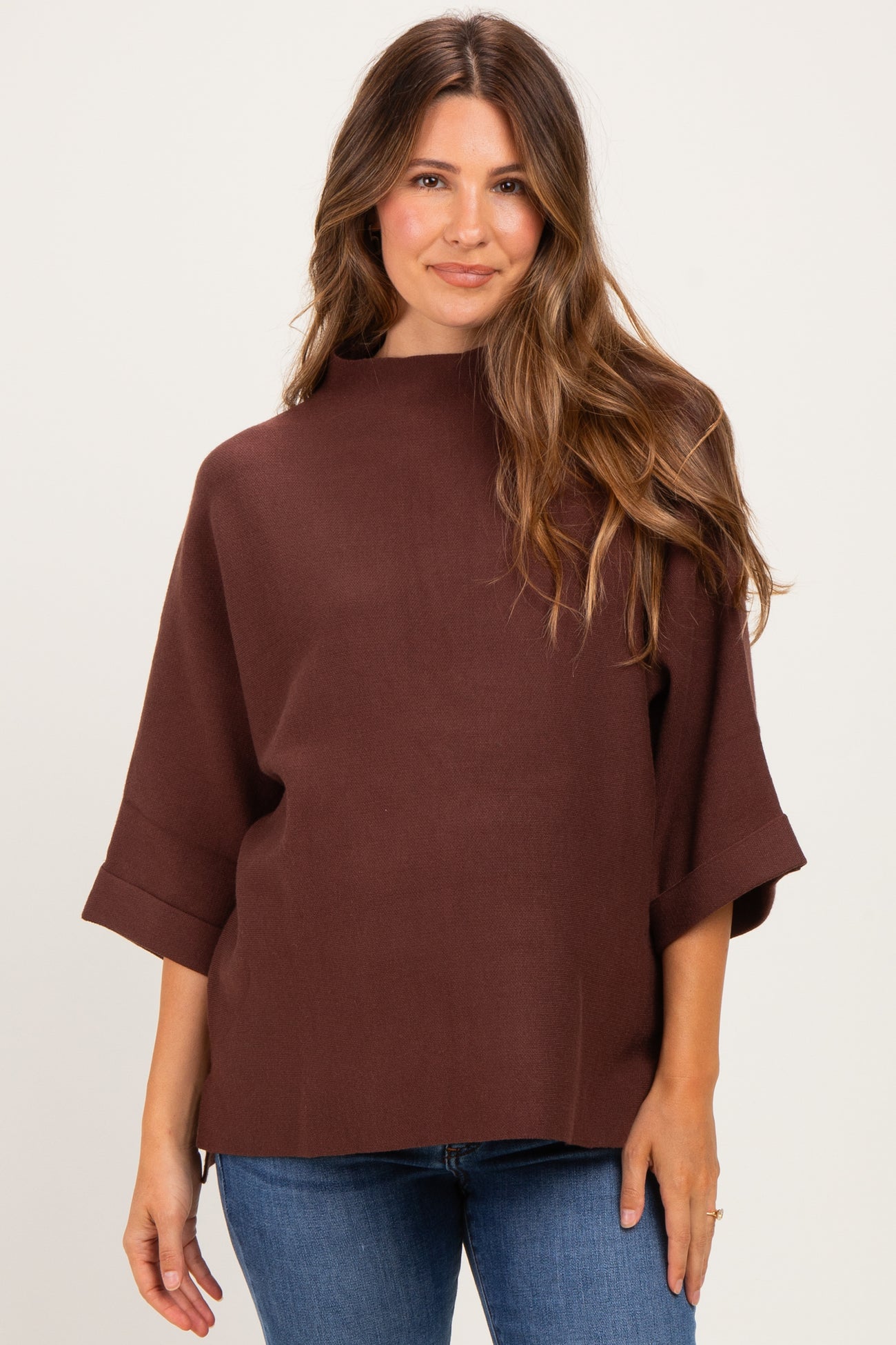 woman wearing a brown maternity top with a high neckline and short sleeves, paired with blue jeans