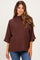 woman wearing a brown maternity top with a high neckline and short sleeves, paired with blue jeans