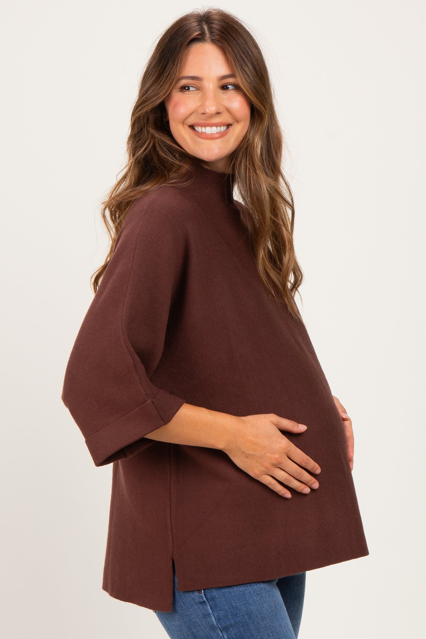 woman wearing a brown maternity top with short sleeves and a relaxed fit, cradling her baby bump