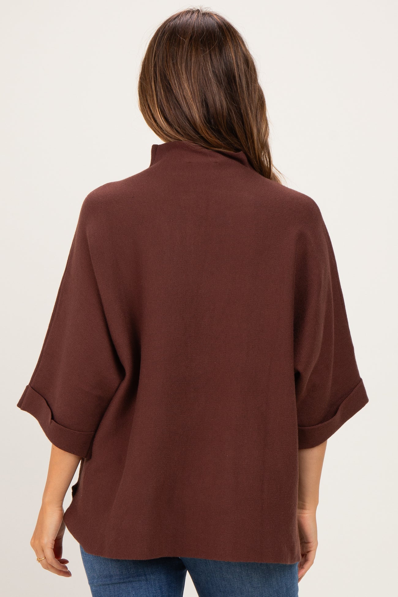 woman wearing a brown maternity top with loose sleeves and a high collar.