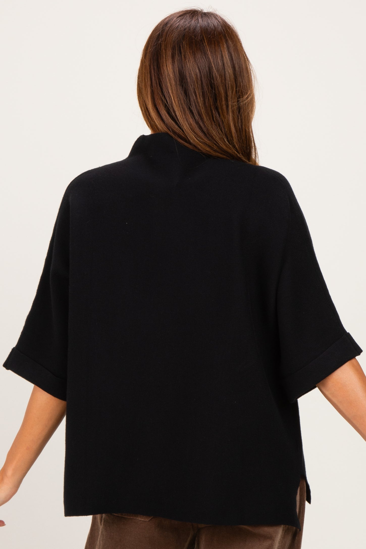 woman wearing a black oversized knit sweater with short sleeves and a relaxed fit