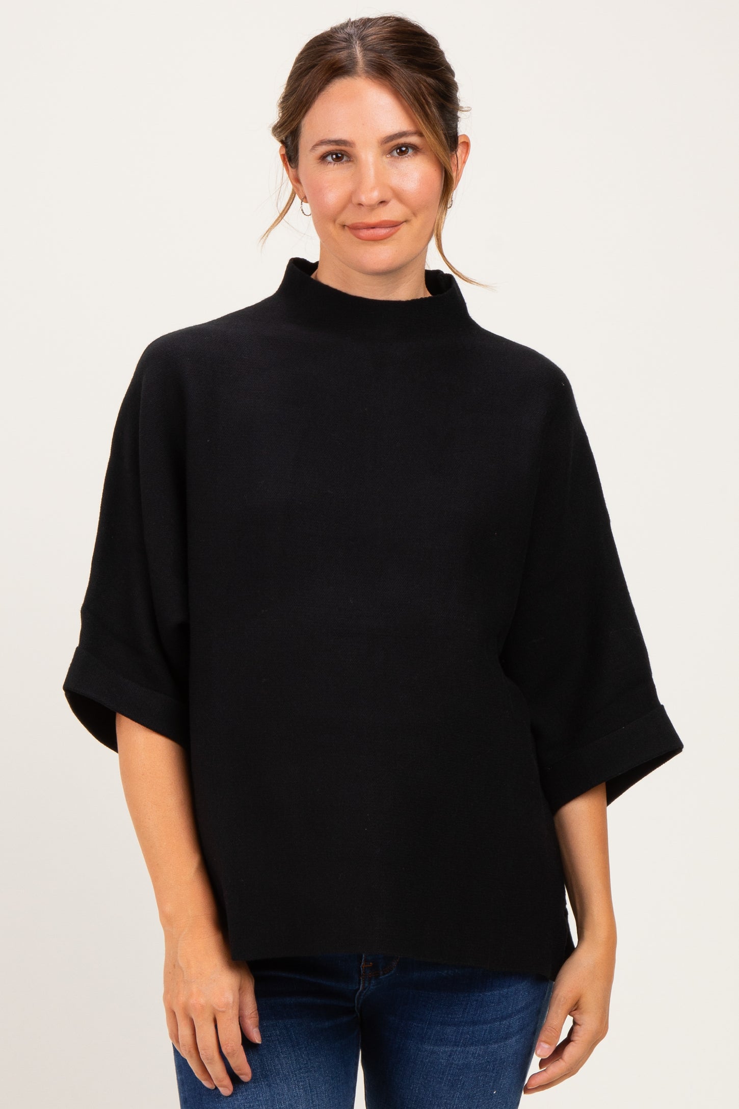 woman wearing a black maternity top with a high neckline and loose sleeves, showing her baby bump