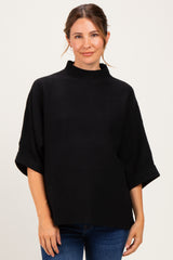woman wearing a black maternity top with a high neckline and loose sleeves, showing her baby bump