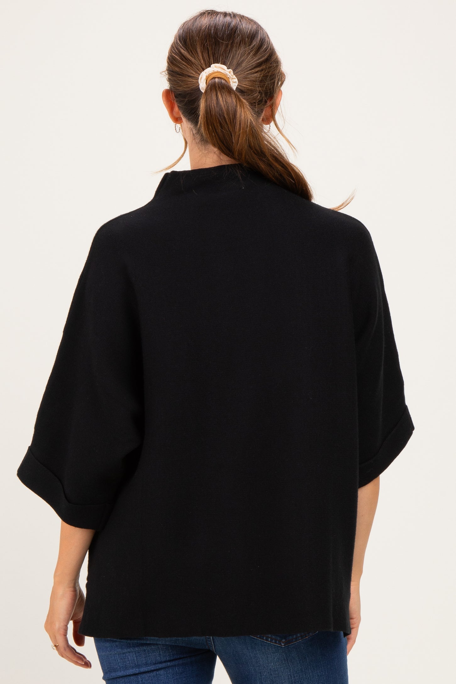 woman wearing a black maternity top with a relaxed fit and three-quarter sleeves, viewed from the back
