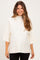 woman wearing a cream maternity top with short sleeves and a high neck, showcasing her baby bump