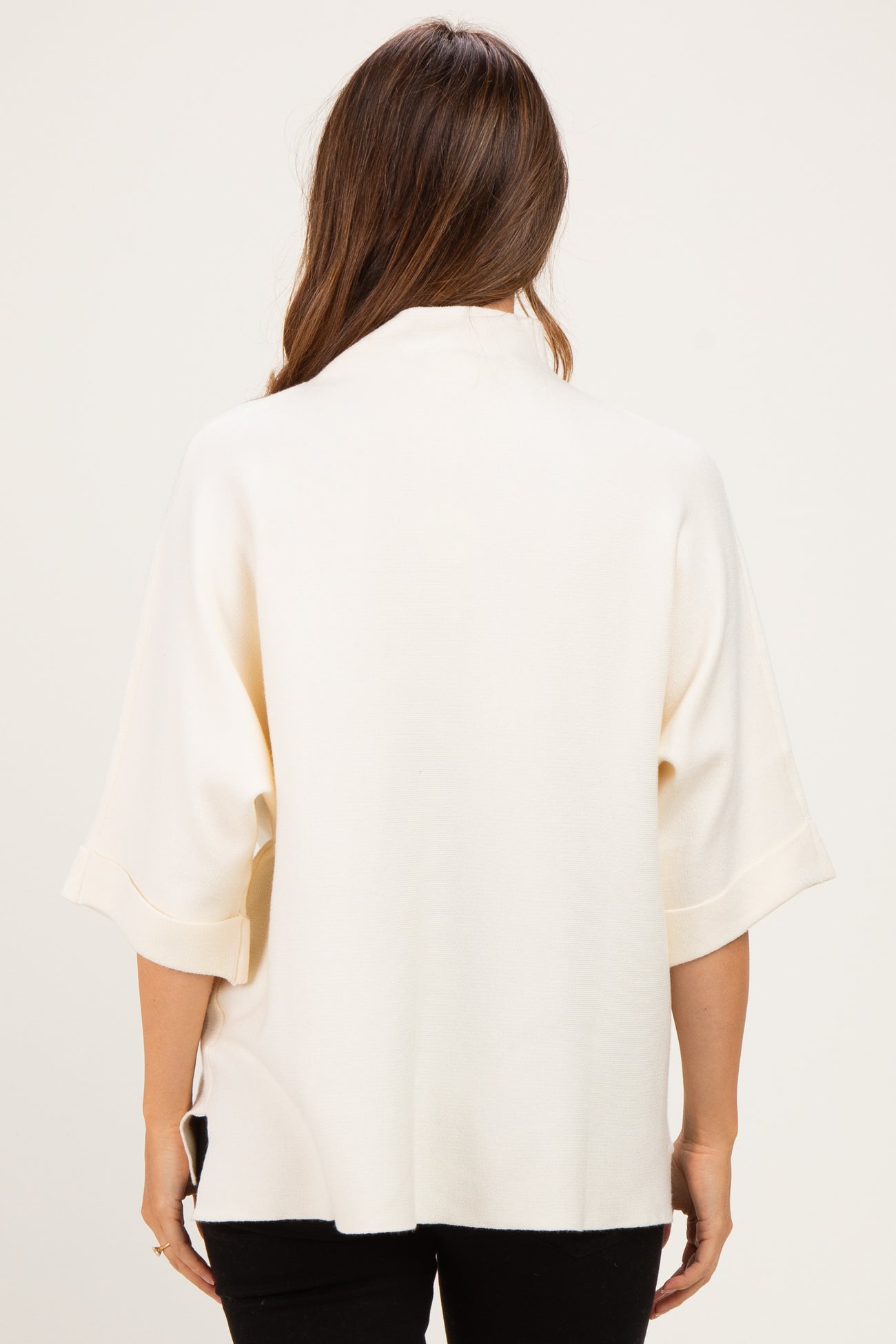 woman wearing a cream maternity top with short sleeves and a relaxed fit, showing the back view