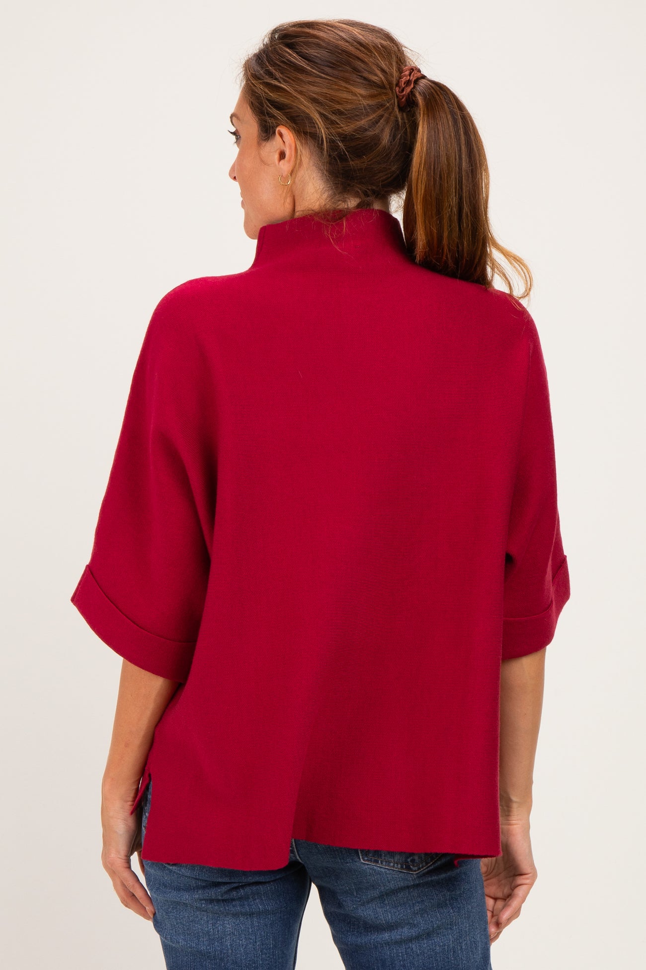 woman wearing a red oversized sweater with a mock neck and wide sleeves, viewed from the back