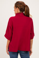 woman wearing a red oversized sweater with a mock neck and wide sleeves, viewed from the back