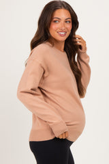 woman wearing a beige maternity sweater with a relaxed fit and visible baby bump