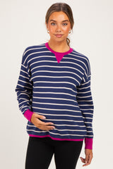 woman wearing a navy and white striped maternity sweater with pink accents and holding her baby bump