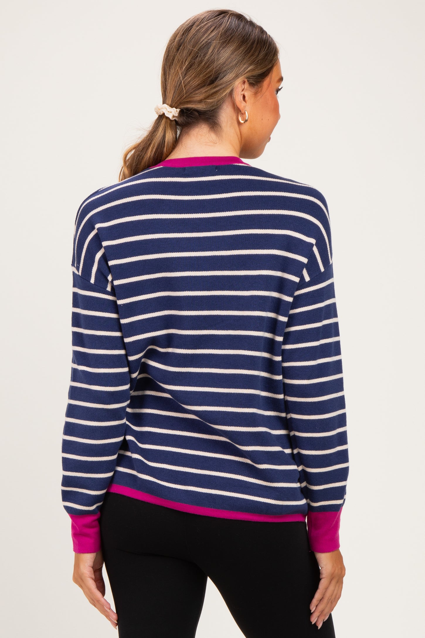 woman wearing a navy and cream striped maternity sweater with magenta cuffs and back view visible