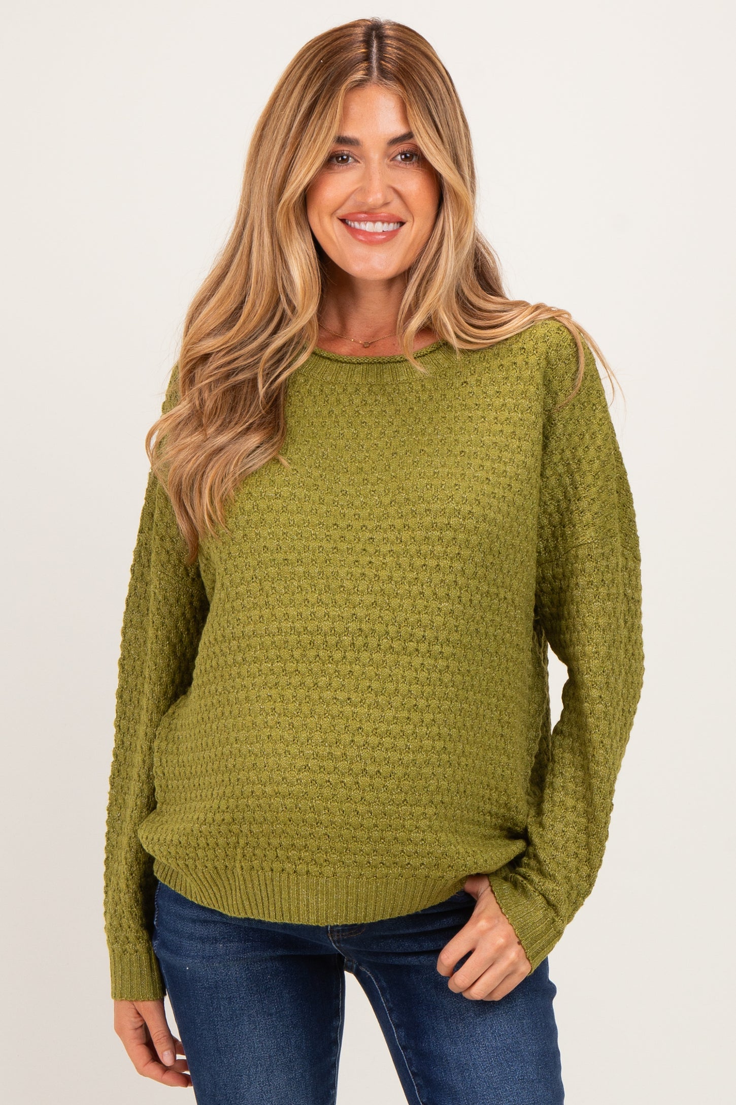 woman wearing a green textured maternity sweater with long sleeves and a relaxed fit, highlighting her baby bump