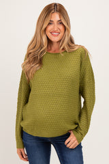 woman wearing a green textured maternity sweater with long sleeves and a relaxed fit, highlighting her baby bump