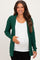 woman wearing a green maternity cardigan over a white top and gently holding her baby bump